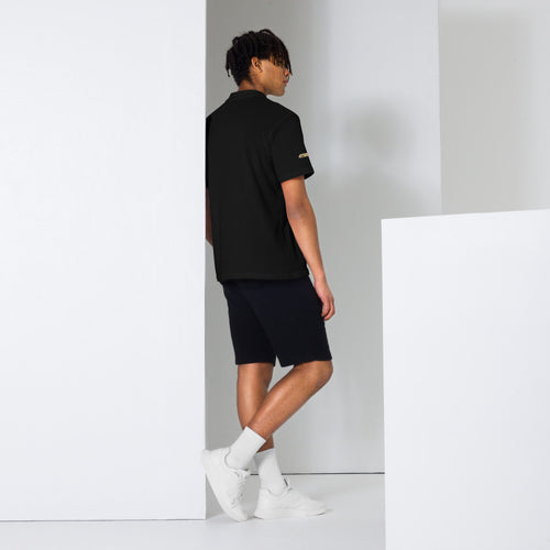 Pickaxe Pique Polo in black, back view, featuring gold pickaxe chest logo